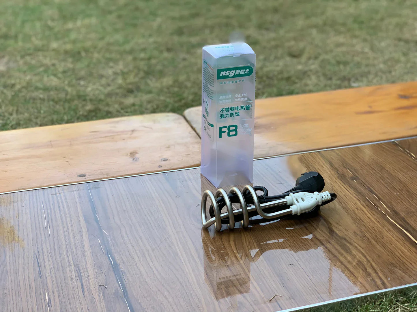 NGK spark plug on a wooden surface with grass in the background